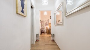 Ein Korridor mit Holzboden, weißen Wänden und einem gerahmten Kunstwerk links.