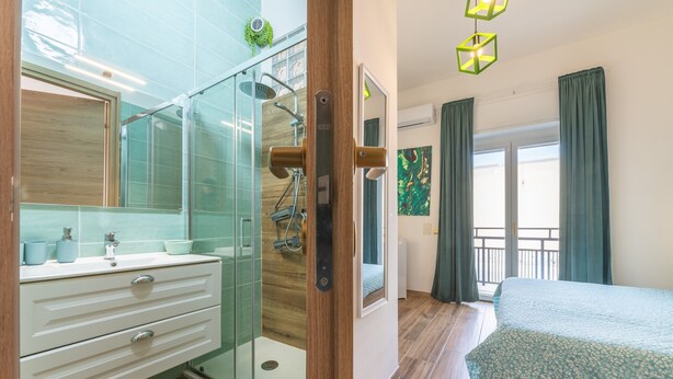 Ein modernes Badezimmer mit Duschkabine aus Glas, einer Holztür und einem weißen Waschtisch mit Schubladen.