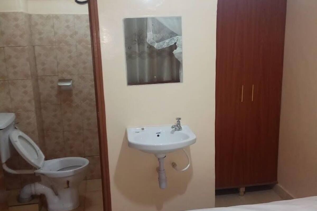 Ein Schlafzimmer mit einem Bett, einem weißen Waschbecken und einem Holzschrank.