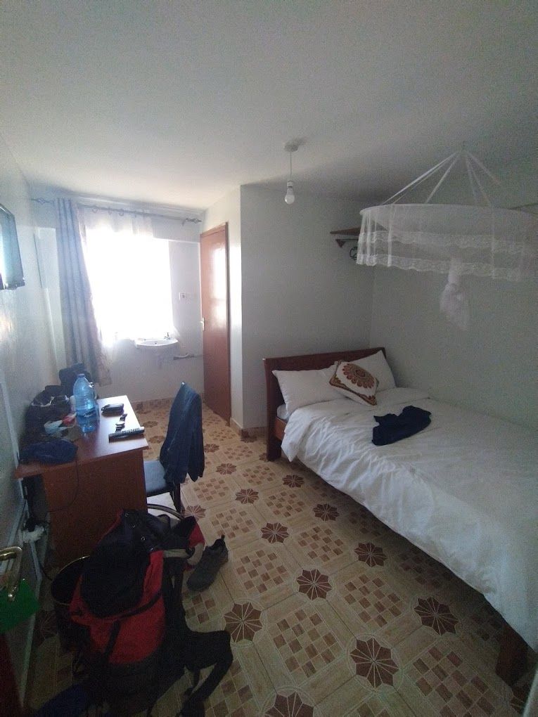 Ein Hotelzimmer mit Bett, Schreibtisch, Stuhl und Koffer.