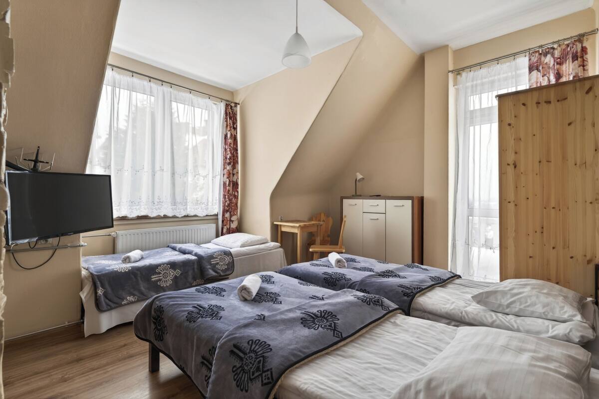 A bedroom with two beds, a TV, a desk, and a wardrobe.