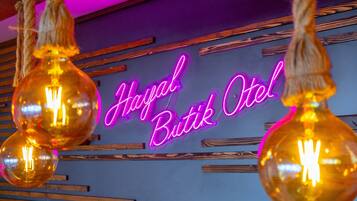 Letrero de neón con el texto 'Hoyal Butik Otel' sobre una pared azul con listones de madera.