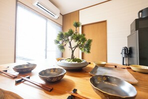 A traditional Japanese room with tatami flooring, a bonsai tree centerpiece, and a kitchen area with a refrigerator and stove. - STAY GATE Nishi-shinjuku gochome.57 ㎡ private hotel. 4min train to Shinjuku Sta. (shibuyaku honmachi)