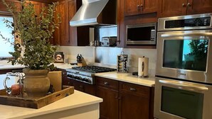A modern kitchen with wooden cabinets, stainless steel appliances, and a central island with a potted plant.