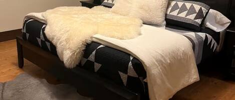 A neatly arranged bedroom with a bed, pillows, a bedside table, and a lamp.