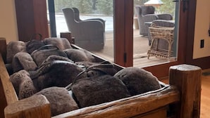 A wooden bench with a view of outdoor furniture and trees through glass doors.
