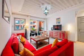 A living room with a red sofa, a wooden coffee table, and a TV on a cabinet. - Cosy 1BR près Carré Eden – Terrasse & Confort (Marrakesh)