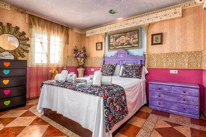 Ein Schlafzimmer mit Bett, Schminktisch, Spiegel und einem Fenster mit Vorhängen.