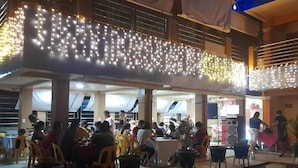 Un área de comedor al aire libre con mesas y sillas, decorada con luces de cadena.