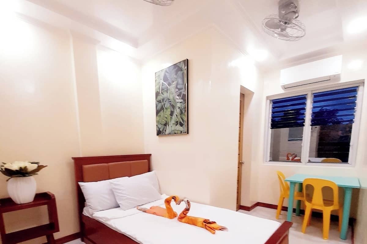 A neatly arranged bedroom with a bed, bedside table, and a small table with chairs.