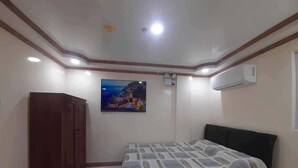 Un dormitorio con cama, armario, un cuadro y aire acondicionado.