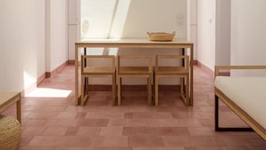 Et moderne interiør med ovenlys, et træspisebord med stole og en flettet kurv på bordet.