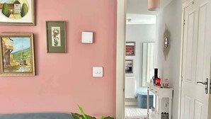 Un salon avec un canapé bleu, une grande plante en pot et des œuvres d’art encadrées accrochées au mur.