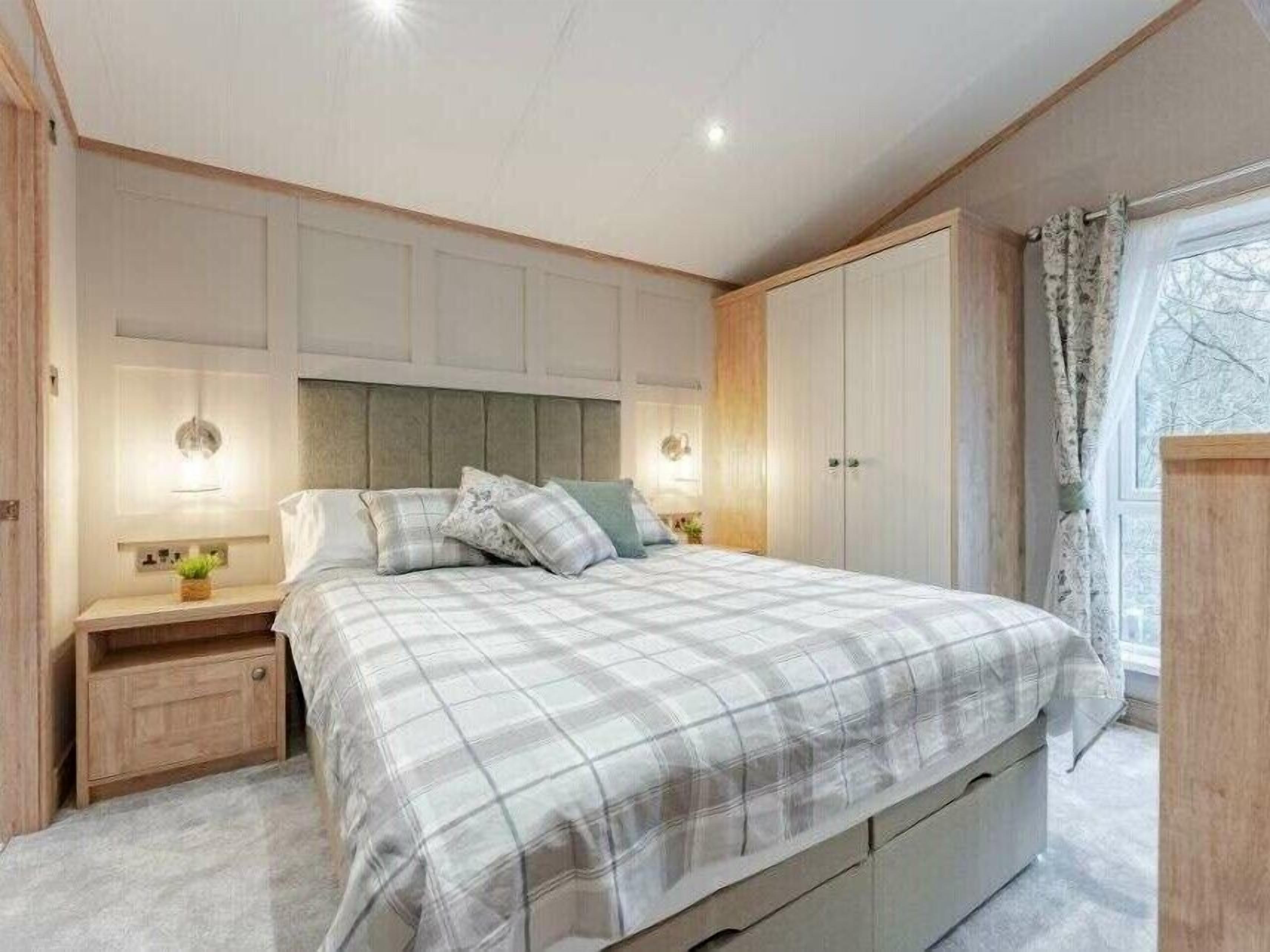 Une chambre à coucher avec un grand lit, des tables de chevet, une armoire et une fenêtre avec des rideaux.