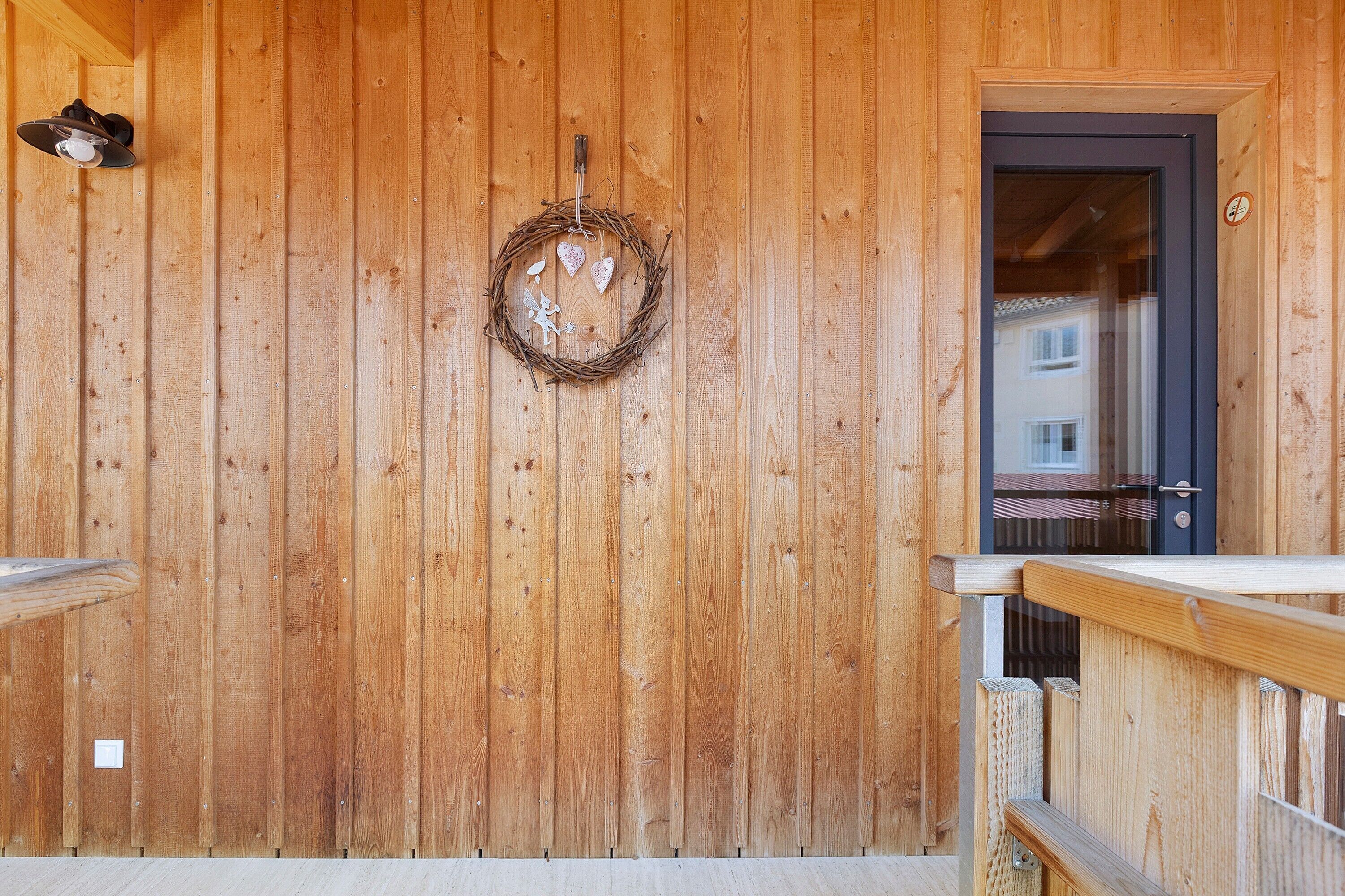 A wooden wall with a wreath, a door, and a railing.