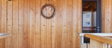 A wooden wall with a wreath, a door, and a railing.