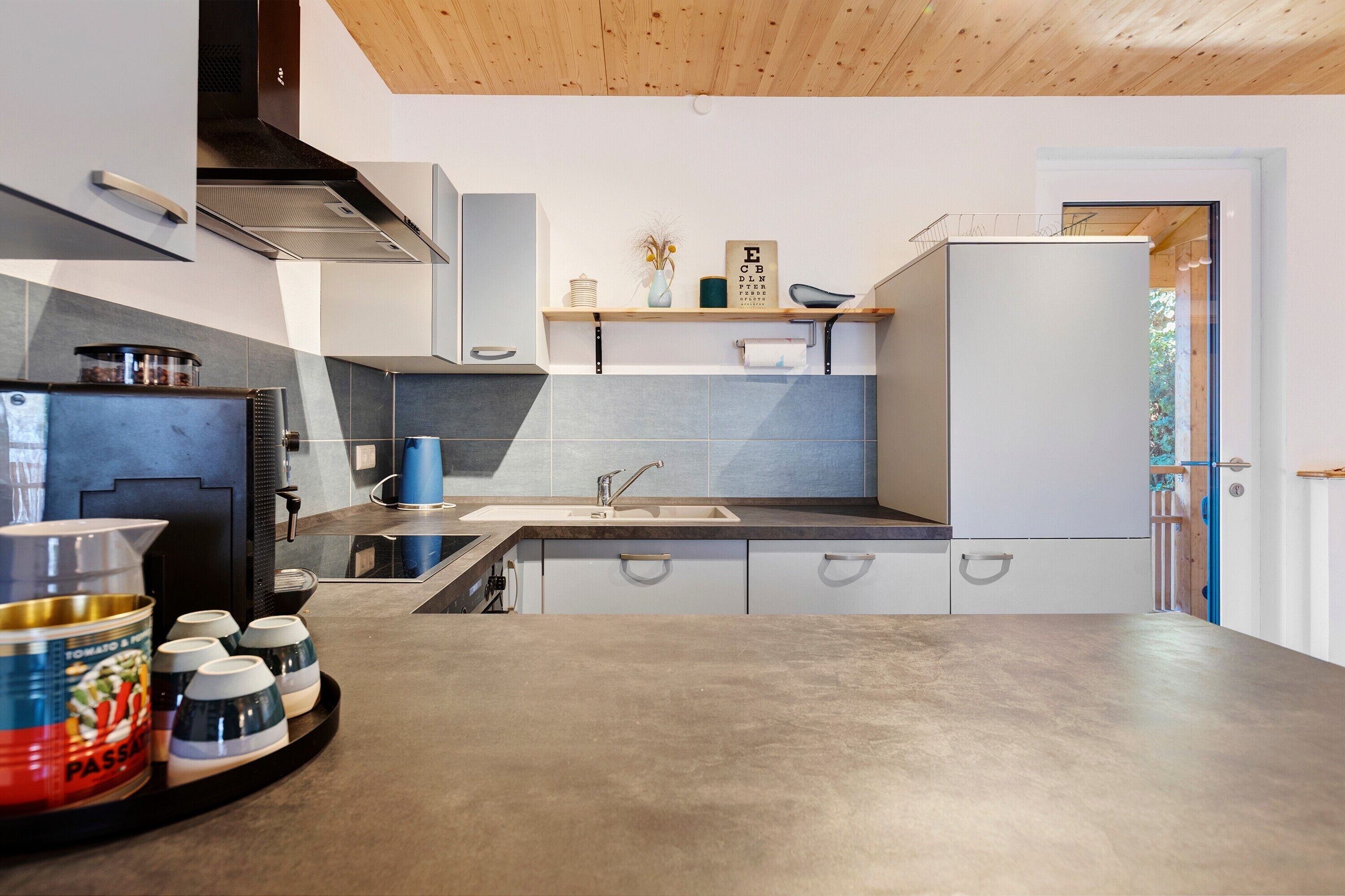 A modern kitchen with a sink, cabinets, and a refrigerator.