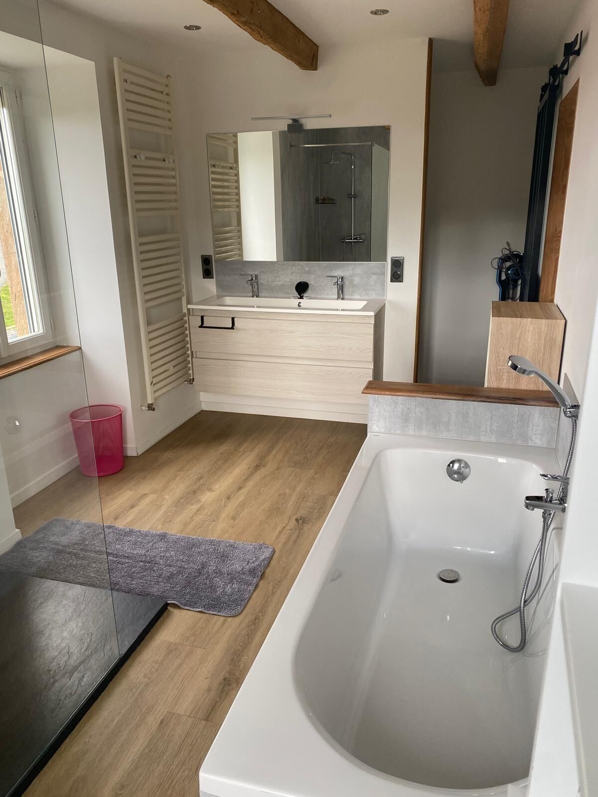 Une salle de bain moderne avec une grande baignoire, un meuble-lavabo à deux vasques et un grand miroir.