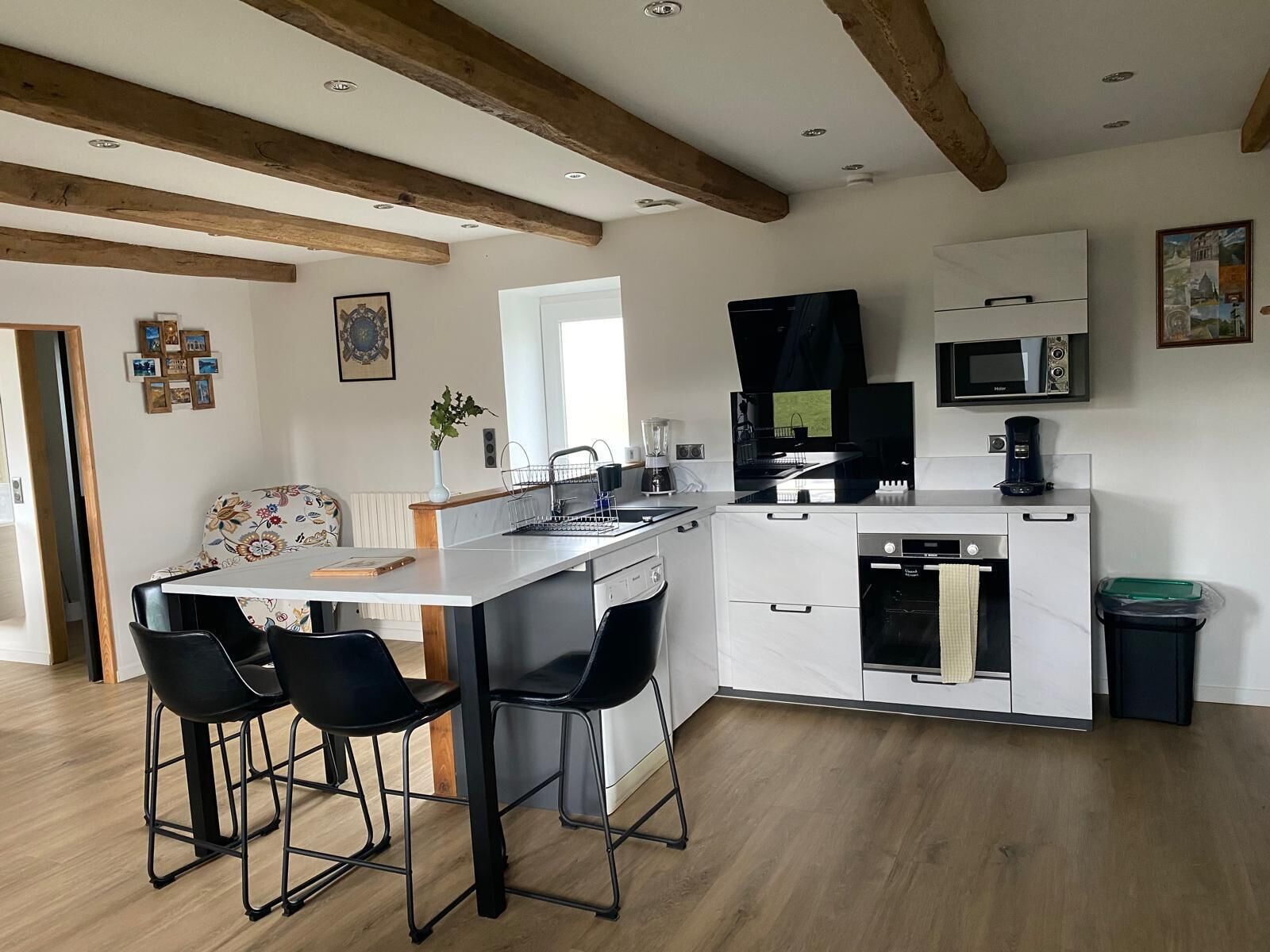 A modern kitchen with a central island, bar stools, a microwave, and a dishwasher.