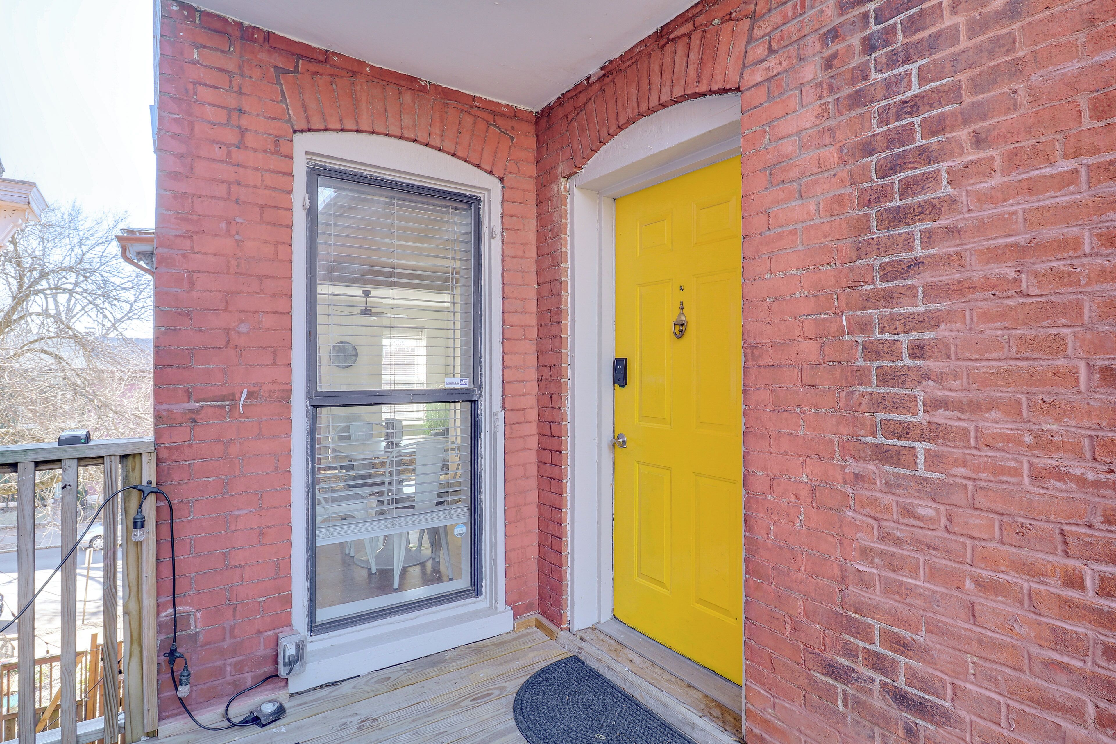 A brick exterior with a yellow door and a window with blinds.