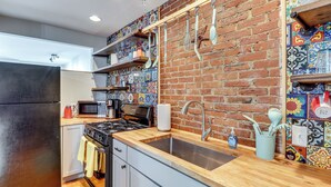 A kitchen with a brick wall, wooden countertop, stainless steel sink, and modern appliances. - Downtown St. Louis Near Arch & Busch Stadium (St. Louis)