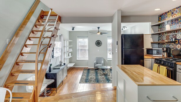 A modern kitchen with a wooden staircase, a dining area with a round table, and a kitchen island. - Downtown St. Louis Near Arch & Busch Stadium (St. Louis)