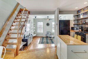 A modern kitchen with a wooden staircase, a dining area with a round table, and a kitchen island. - Downtown St. Louis Near Arch & Busch Stadium (St. Louis)