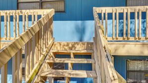 Un escalier en bois mène à un bâtiment bleu doté d’une fenêtre.