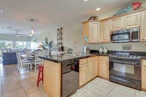 A modern kitchen with wooden cabinets, stainless steel appliances, and a central island with seating. - Boat, Swim, Walk to Beach! Dauphin Island Retreat (Dauphin Island)