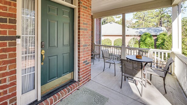 A brick house with a green door, a porch with a table and chairs, and a view of a neighboring house. - 2 Mi to Pinehurst Resort: Spacious Golf Getaway! (Pinehurst)