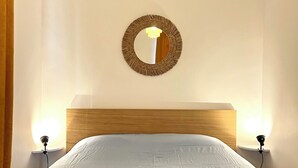 Una habitación de hotel con una cama, un espejo redondo en la pared y dos lámparas de noche.