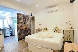A bedroom with a large bed, bedside tables, an air conditioning unit, and a view of the adjacent room. - Casa Armonia-Arco Iris Peace in the middle of a small oasis (Benissa)