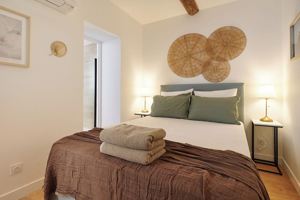 A bedroom with a large bed, two bedside lamps, a headboard with circular wall art, and a door leading to another room.