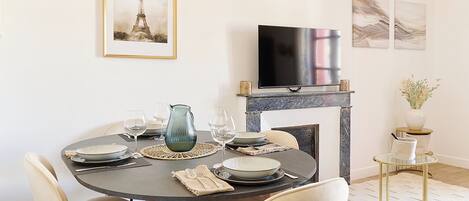 A dining area with a round table, chairs, and a television above it.