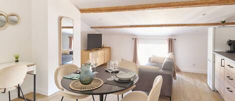A modern dining area with a wooden ceiling, a dining table set with plates, glasses, and a vase.