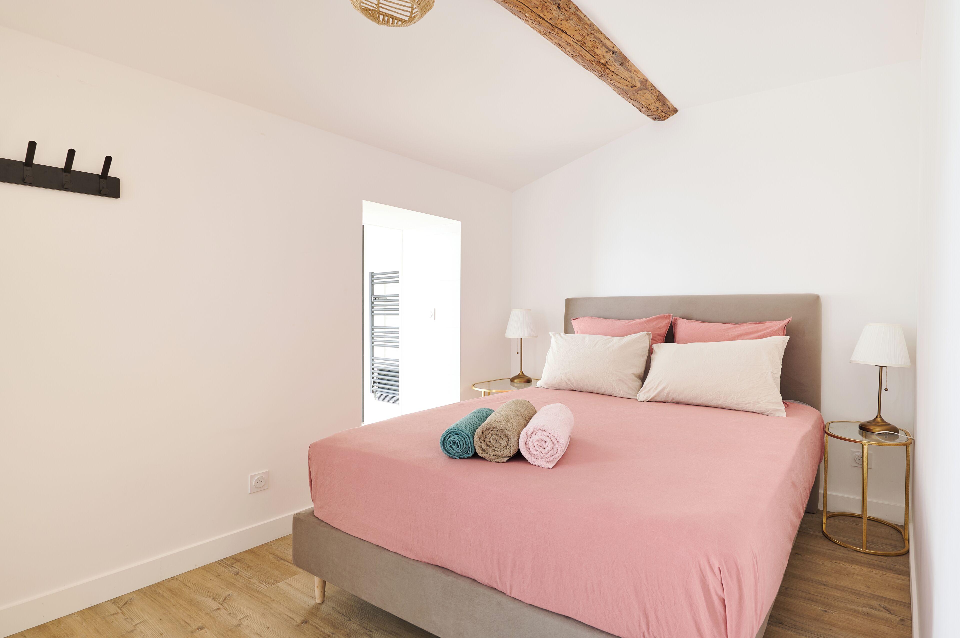 A bedroom with a bed, two bedside tables, a wall-mounted light fixture, and a door.