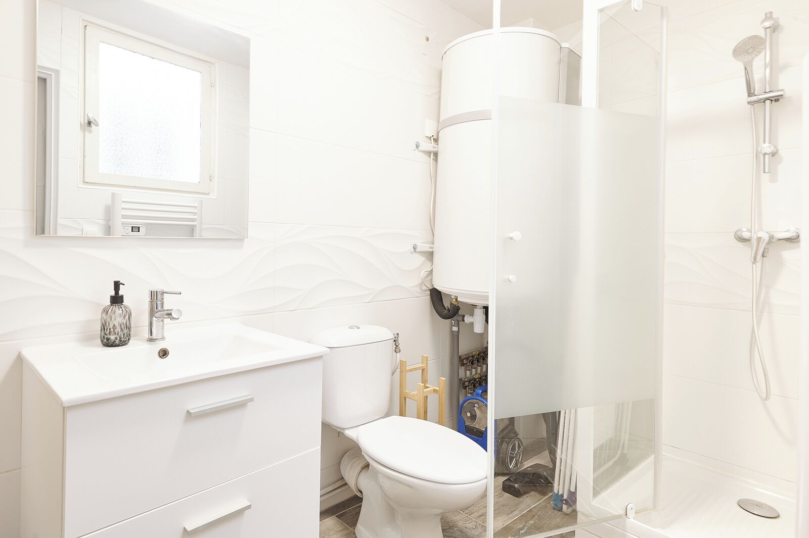 A modern bathroom with a white vanity, a toilet, and a shower area.