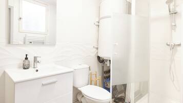 A modern bathroom with a white vanity, a toilet, and a shower area.