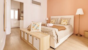 Un dormitorio con cama, mesitas de noche, una lámpara y una ventana.