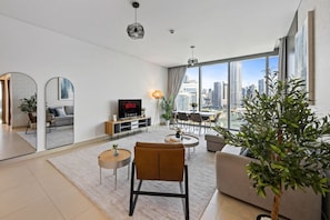 A modern living room with a large TV, a dining area, and a view of the city skyline. - Spacious 2BR in 52|42, Walk to JBR Beach & Marina (Dubai)