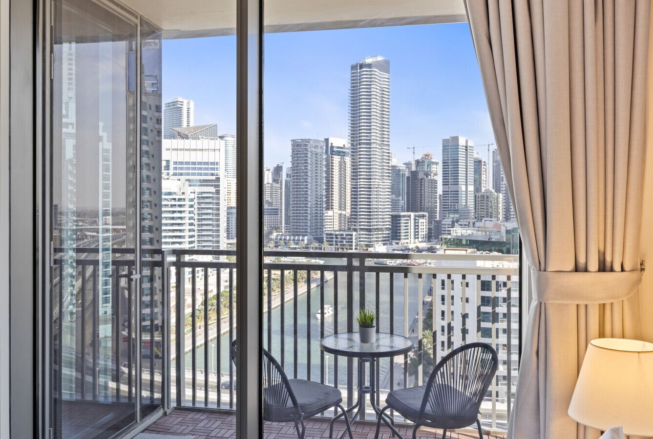 Un balcone con vista sulla città, due sedie, un tavolino e una pianta in vaso.