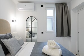 Una camera da letto con un letto, uno specchio, una finestra con tende e un condizionatore d'aria.