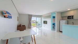 Una cocina moderna con microondas, refrigerador y comedor con mesa y sillas blancas.