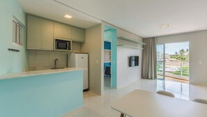 Una cocina moderna con microondas, refrigerador y lavaplatos. Hay un comedor con mesa y sillas.