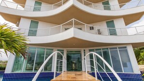 Un hotel de varios pisos con fachada curva, balcones y zona de piscina.