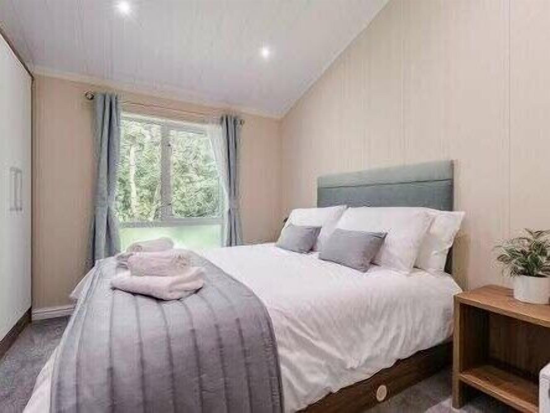 A bedroom with a bed, a window, and a bedside table.