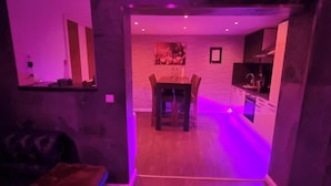Uma sala de estar moderna com área de jantar, cozinha e escada que leva a outro andar.