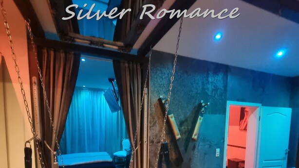 A room with a bed, a swing, and a door leading to another room.
