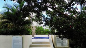 A staircase leading to a pool area, surrounded by lush greenery and a white wall with a sign.
