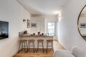 A modern kitchen with white cabinetry, a wooden countertop, and four bar stools. - Quiet Elegance Retreat Apartment Trastevere Family-friendly (Roma)